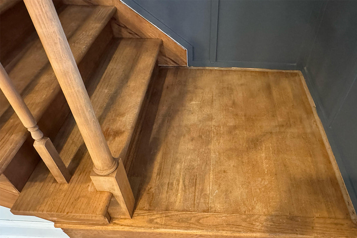 Wooden staircase and railing covered with old varnish, stains and surface residue before laser cleaning restoration.