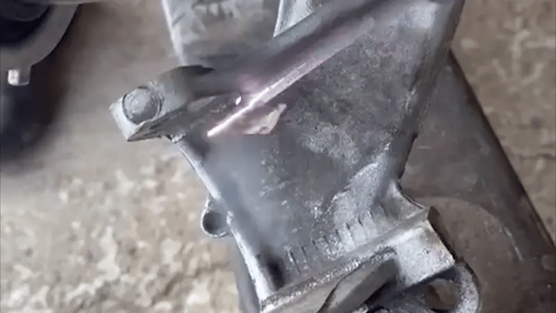 Industrial laser cleaning process removing oil stains and surface grease from a metal part using high-energy, non-contact laser pulses.