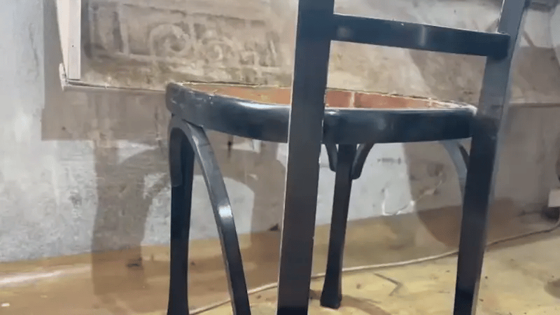 Laser cleaning process removing paint or residue from a wooden chair surface while preserving the natural wood grain.