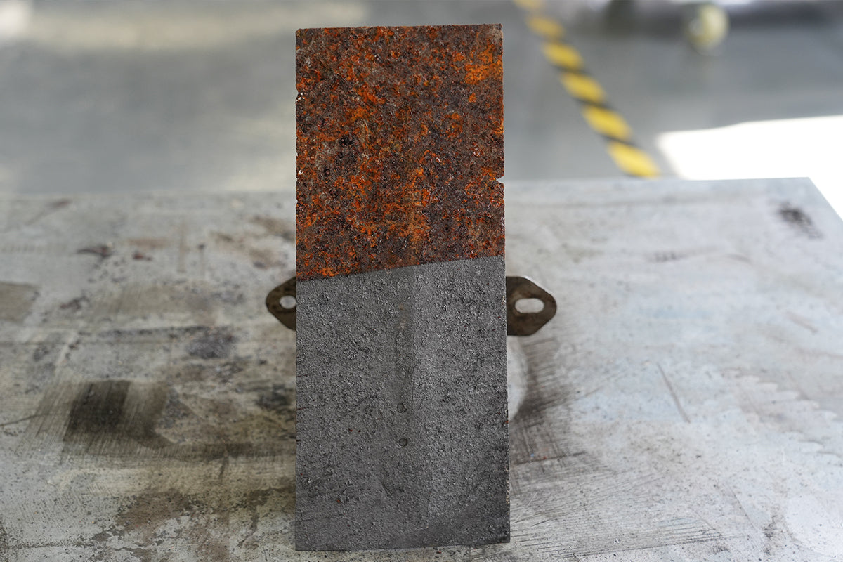 Laser cleaning removes heavy rust from a rectangular steel plate, showing a clear before-and-after surface contrast.