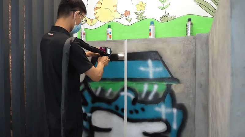 Laser cleaning operator removing graffiti from a concrete wall using a high-precision fiber laser for safe, non-abrasive restoration.