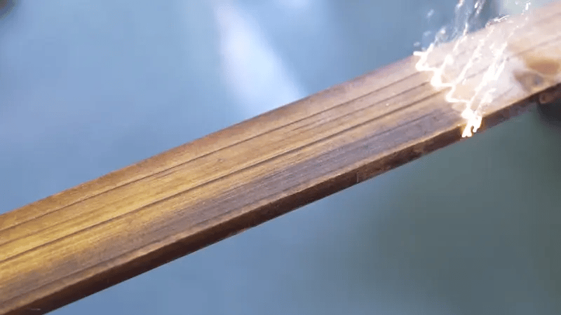 Laser cleaning machine removing soot and oxidation from a wooden surface, restoring natural wood texture without damage.