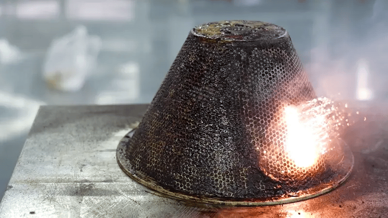 Laser cleaning machine removing oil and grease from a metal mesh component during industrial degreasing.