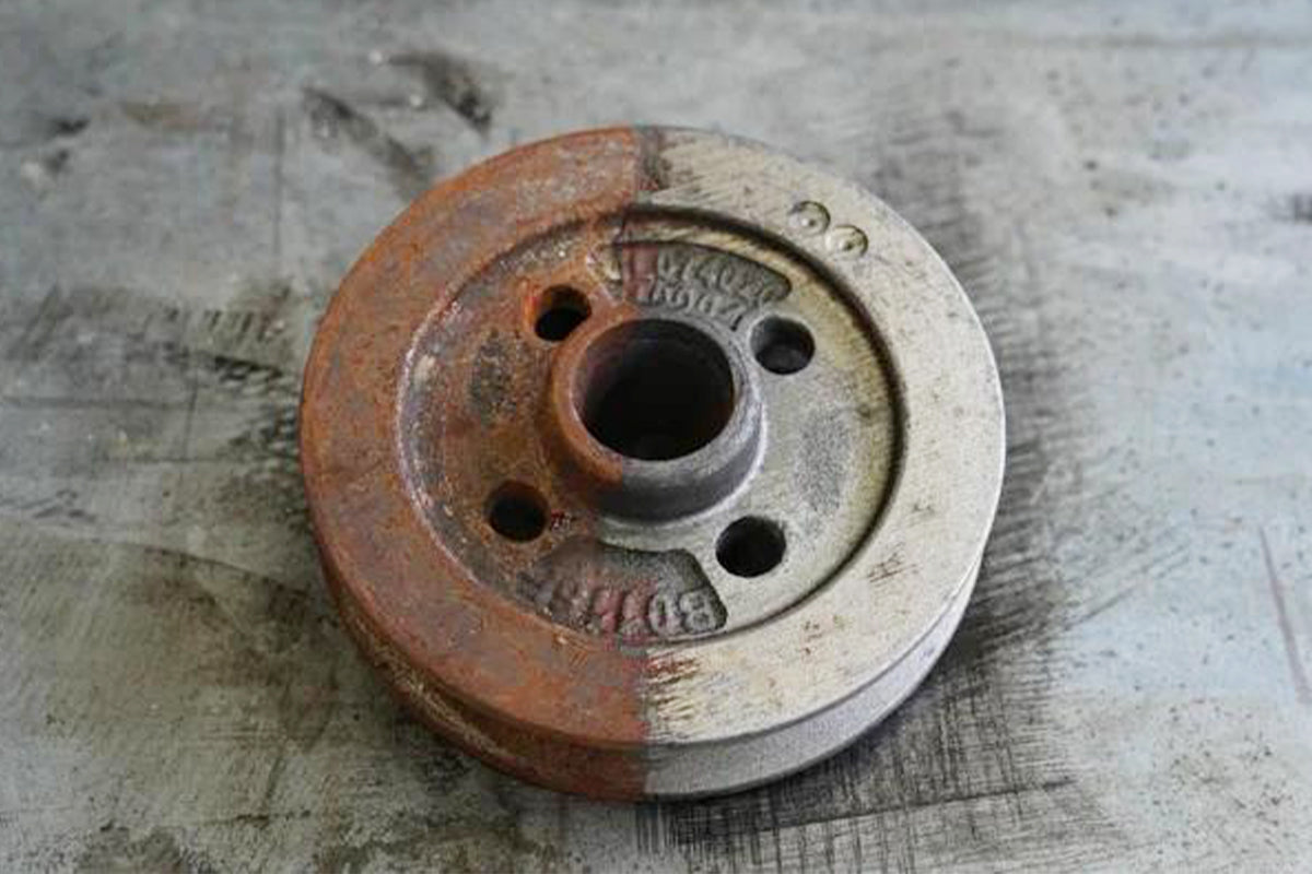 Laser cleaning removes rust from a circular metal pulley, showing a clear before-and-after surface restoration effect.