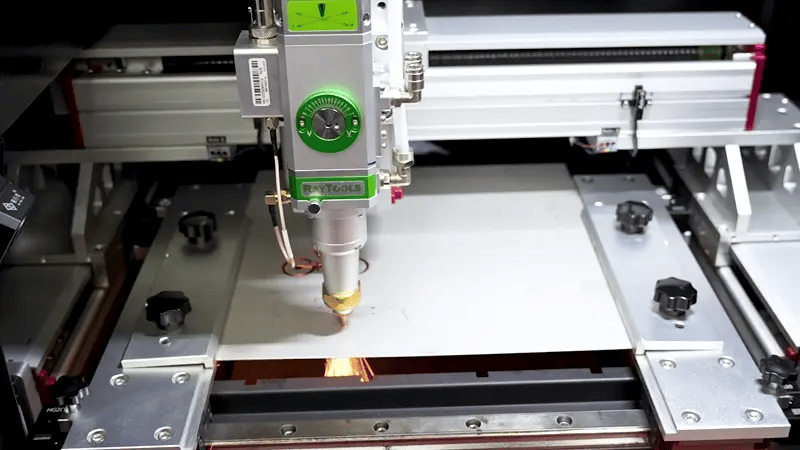 High-speed laser cutting machine processing metal sheets with rapid beam motion and visible cutting sparks.