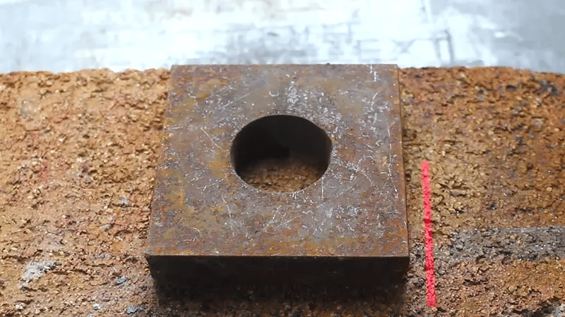 Laser cleaning removing rust and corrosion from a metal block surface, revealing clean steel beneath with precise non-contact laser action.