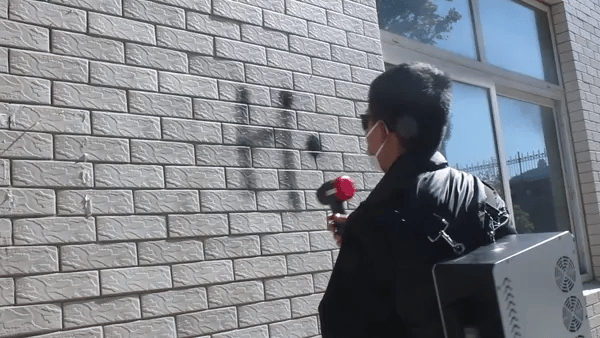 Laser cleaning tool removing graffiti and surface stains from a textured stone wall with precise, non-abrasive laser action.