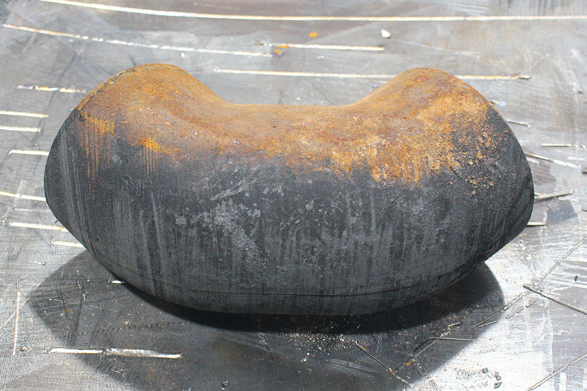 Rust-covered curved metal pipe fitting before laser cleaning, showing oxidation buildup on the surface.