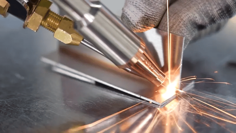 Fiber laser welding close-up showing precise metal joint welding with sparks on stainless steel.